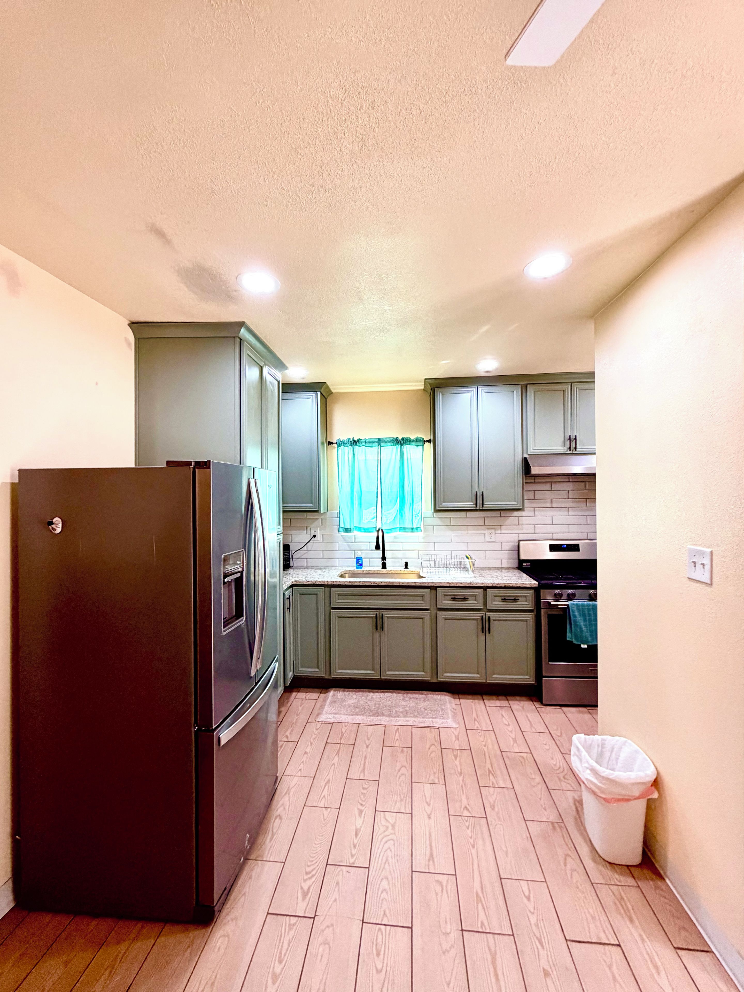 A compact kitchen with a refrigerator, oven, and sink.