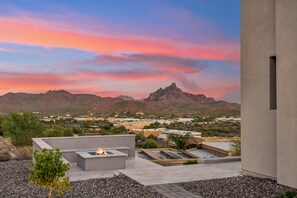 Eine Dachterrasse mit Feuerstelle, Blick auf eine Wüstenlandschaft und ein Gebirge im Hintergrund.