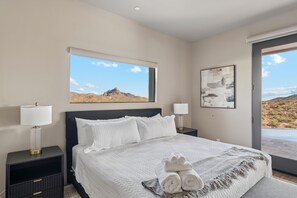 Ein Schlafzimmer mit einem Bett, zwei Nachttischen, einem Fenster mit Blick und einem Bild an der Wand.