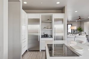 A modern kitchen with built-in appliances, a dining area with a white table, and a seating area with a sofa and a chair. - The Mountain Watch | Infinity Pool & Casita (Fountain Hills)