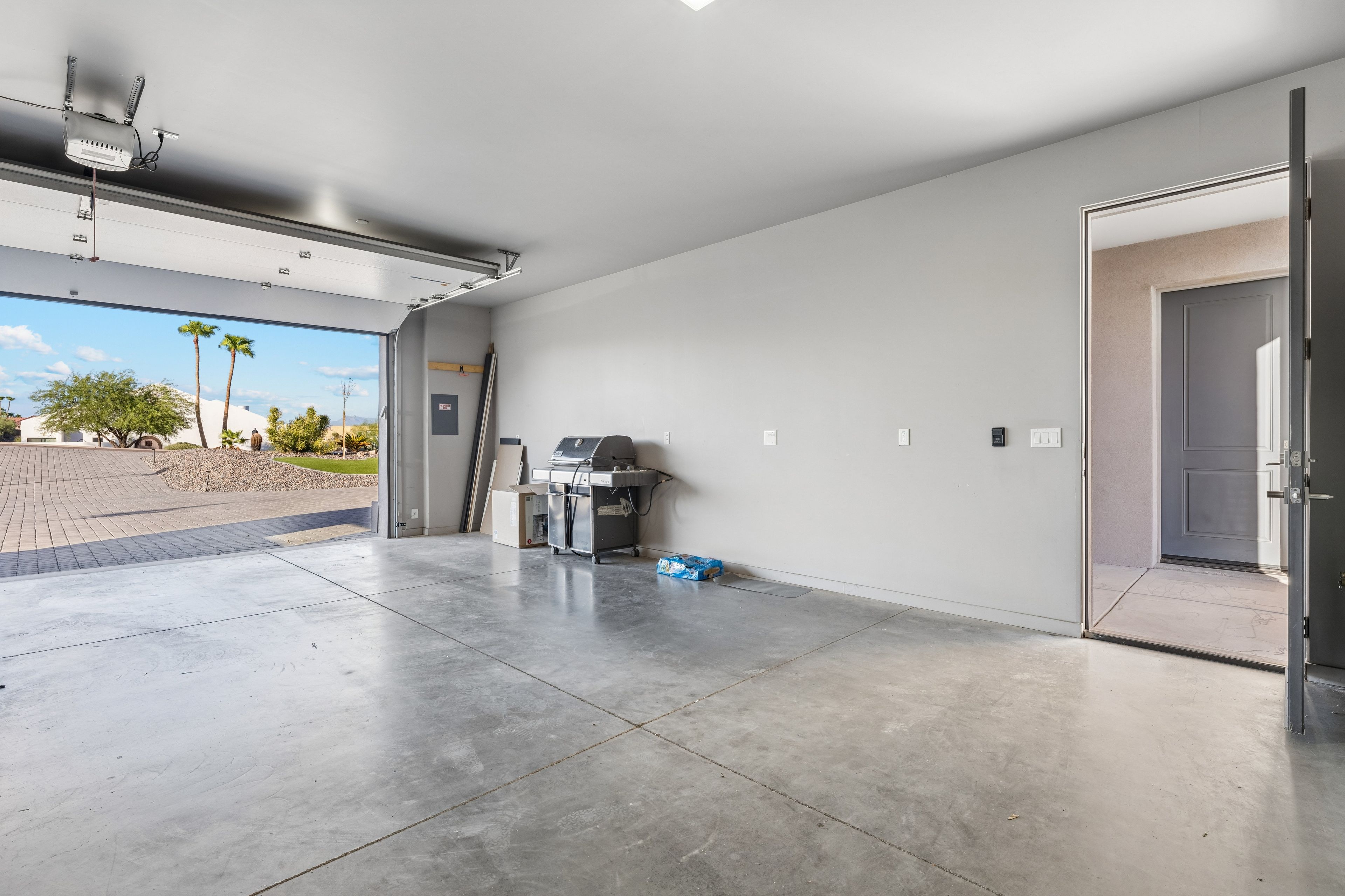 A spacious garage with a concrete floor, a ceiling-mounted projector, and a door leading outside.