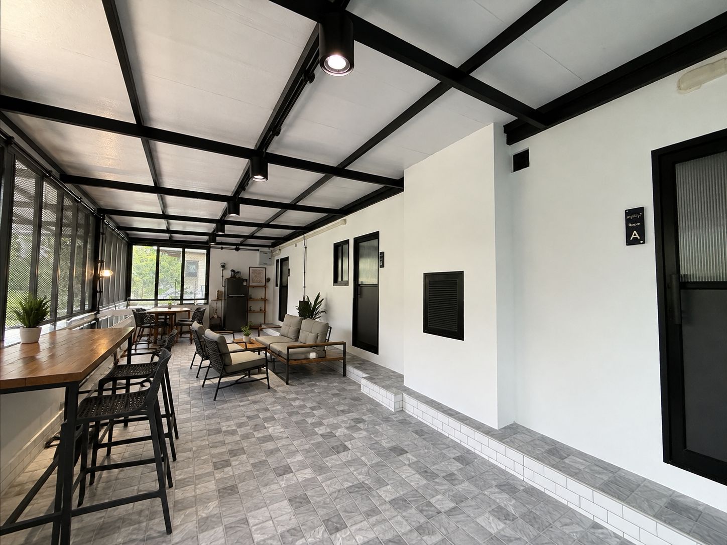 A spacious room with a high ceiling, a dining area with a long table and chairs, and a seating area with sofas and a coffee table.