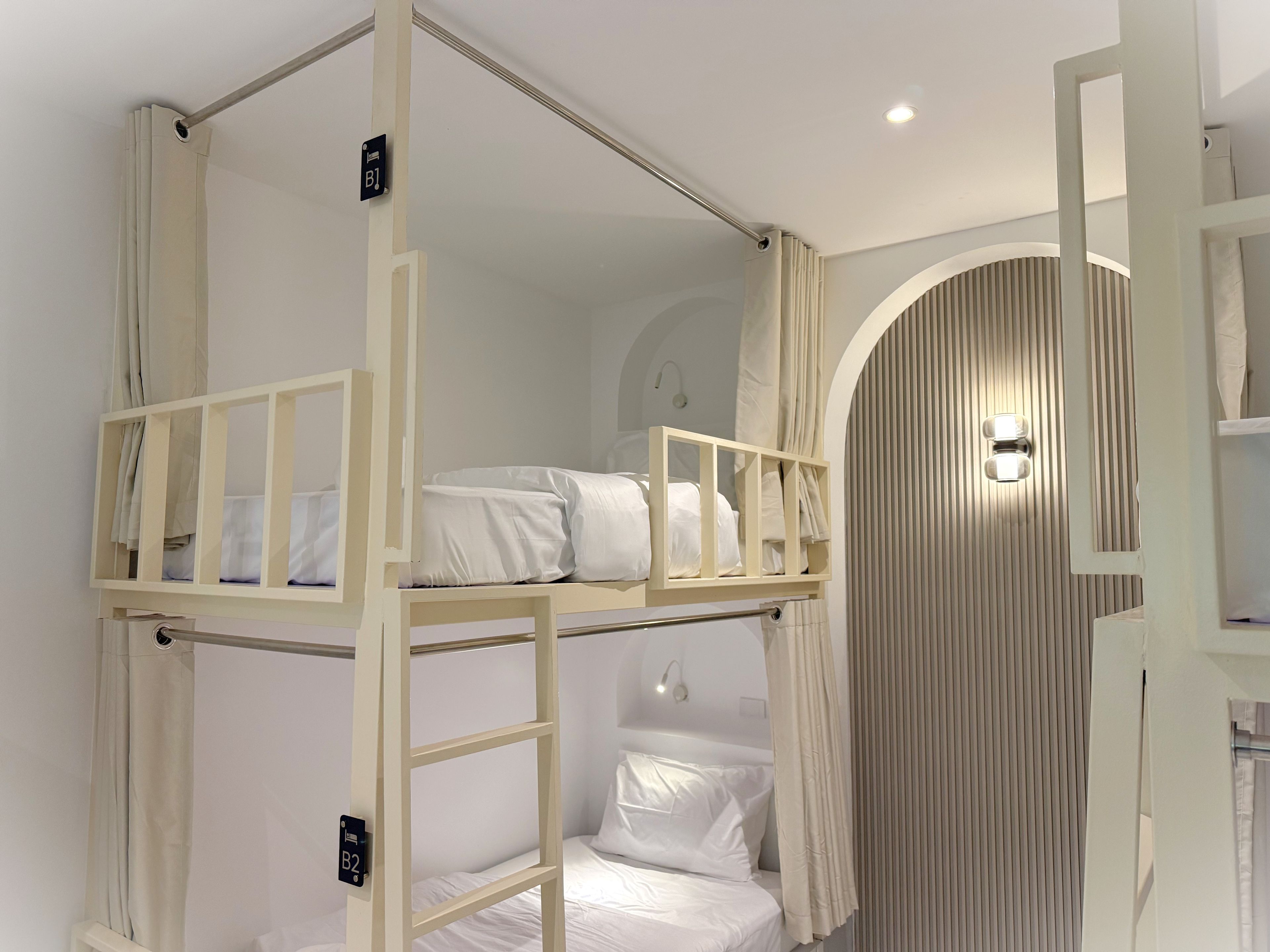A bunk bed room with a ladder, a curtain, and a wall-mounted light fixture.