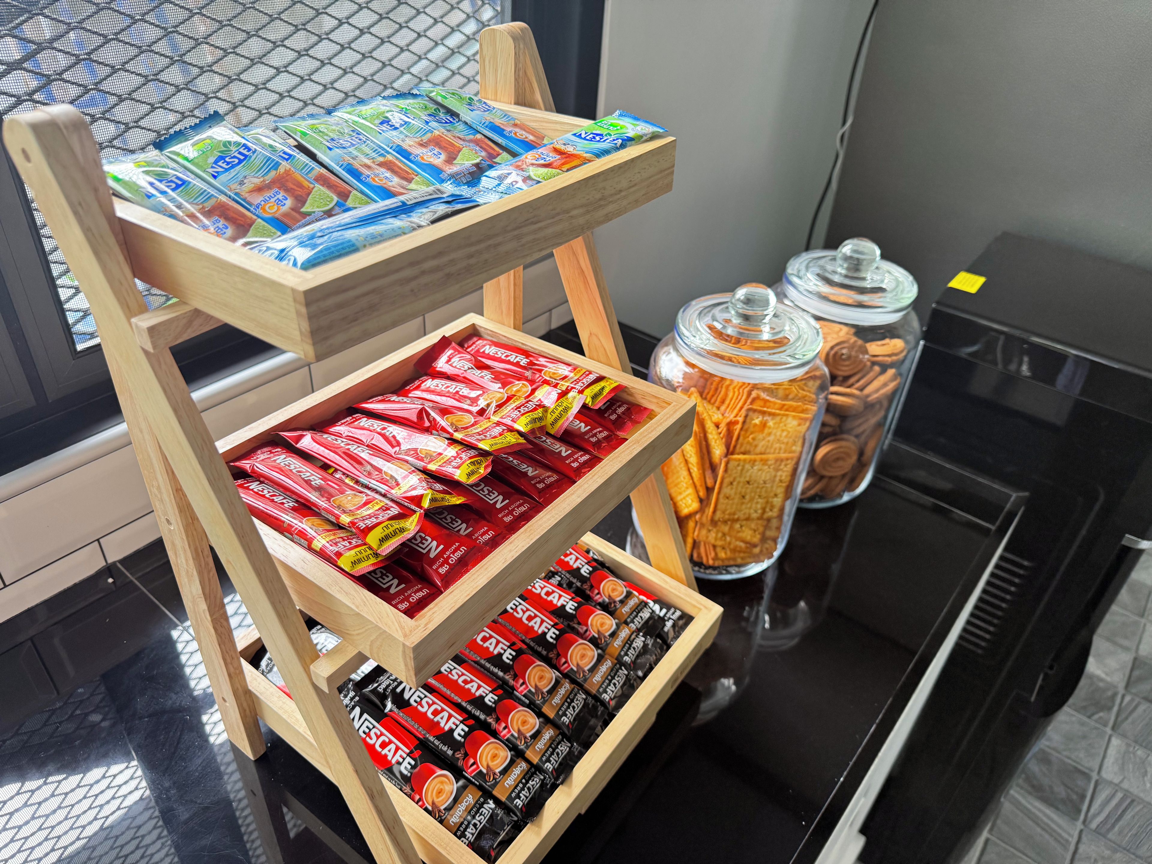Un présentoir en bois à plusieurs niveaux, où sont exposés divers produits et en-cas de la marque Nescafé.