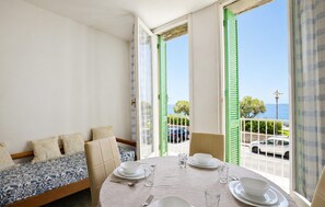 A balcony with a dining table set for two, a sofa, and a view of the sea. - 2 bedroom stunning apartment in Deiva Marina (Deiva Marina)