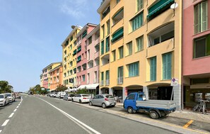A street with multi-story buildings, parked cars, and a blue delivery truck. - 2 bedroom stunning apartment in Deiva Marina (Deiva Marina)