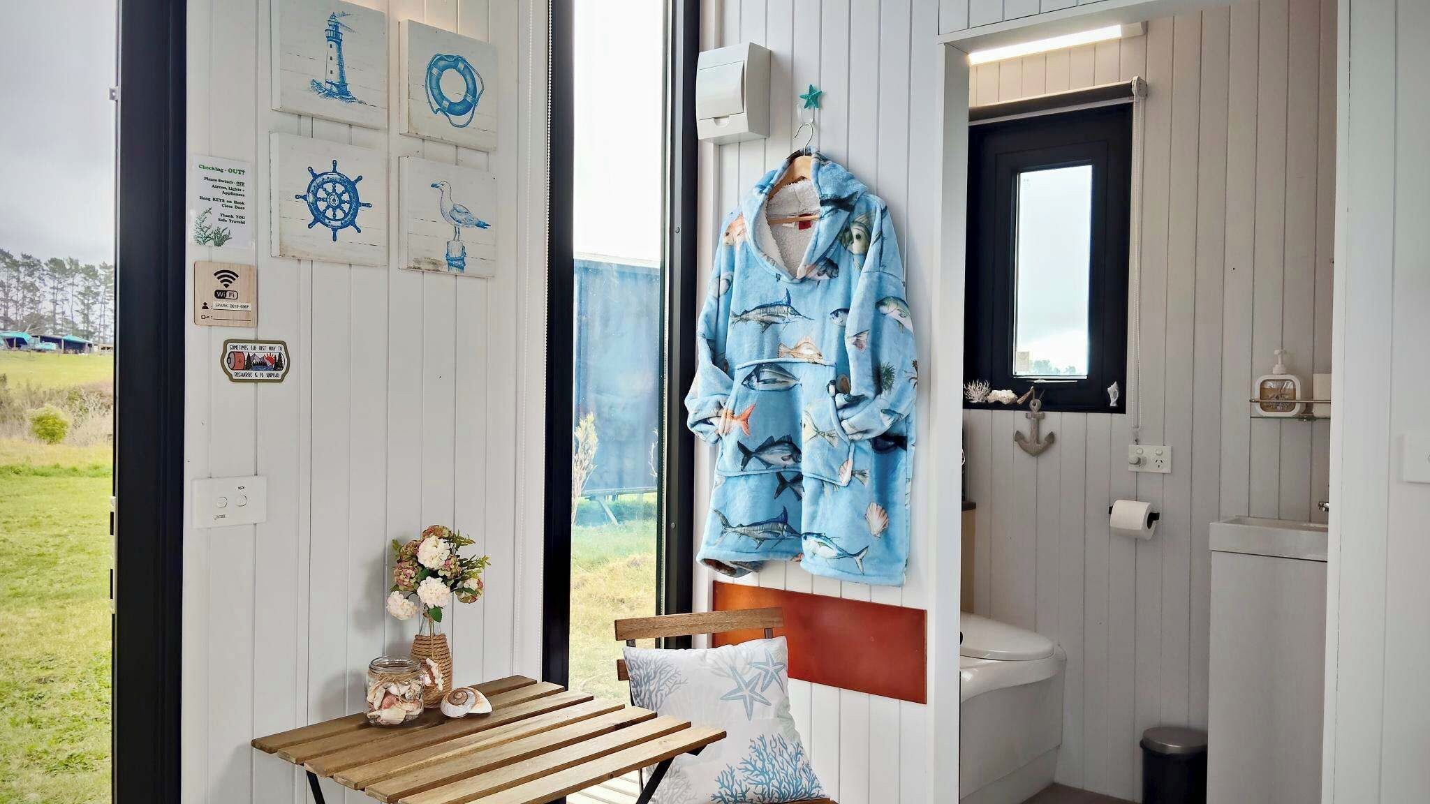A room with a wooden table, a bench, a wall-mounted towel rack, and a view of the outdoors.