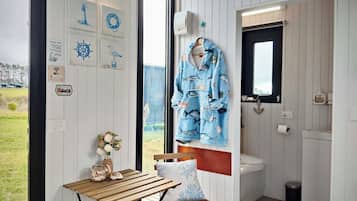 A room with a wooden table, a bench, a wall-mounted towel rack, and a view of the outdoors.
