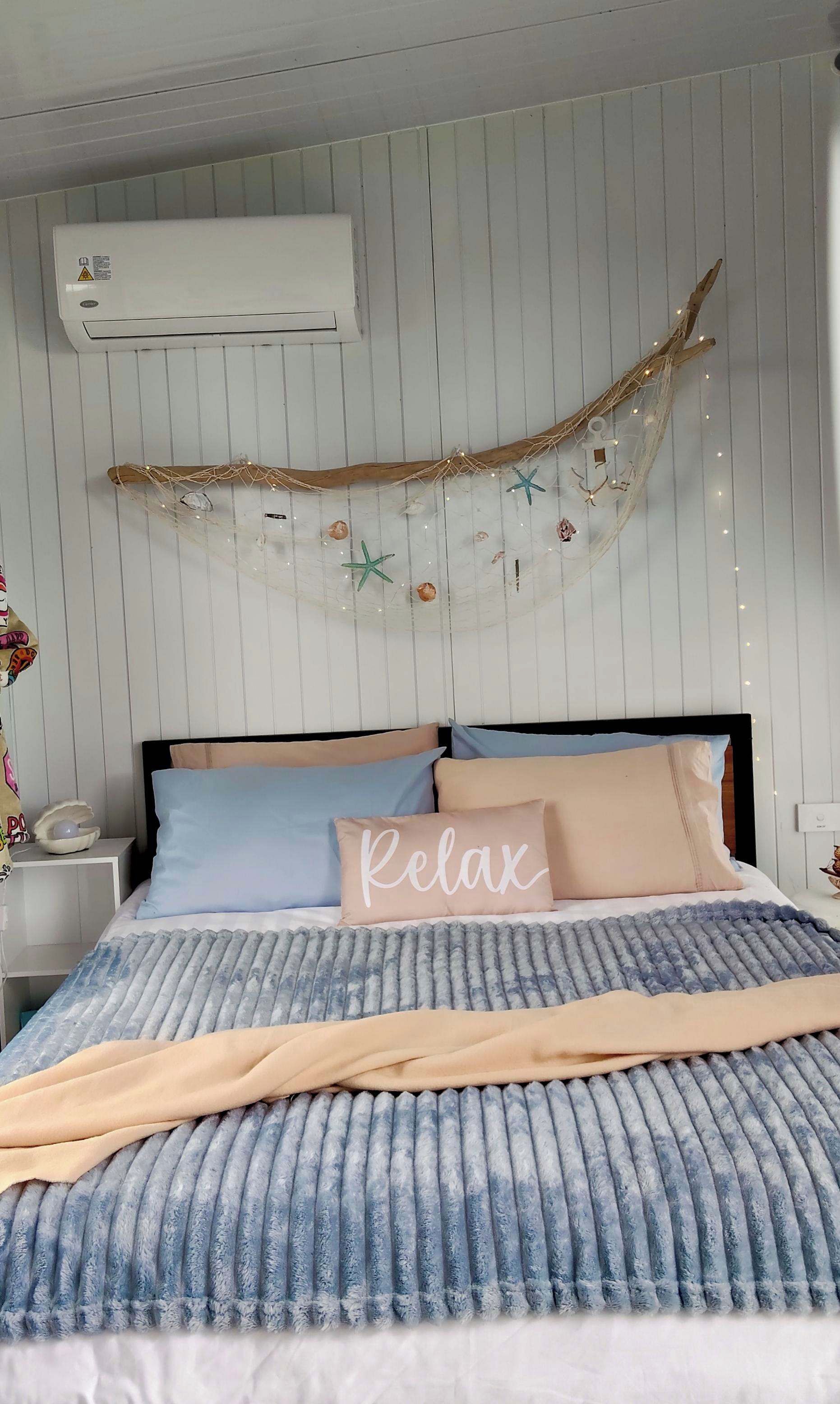 Ein Schlafzimmer mit Bett, Kissen, Decke, einer Klimaanlage und einer dekorativen Girlande.