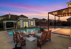 Ein Garten mit Swimmingpool, Sitzgelegenheit im Freien und einer Pergola.