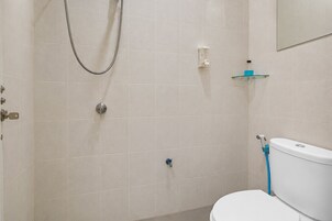 Un baño con inodoro, ducha y estante de vidrio.