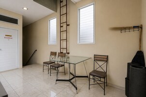Un comedor con mesa de vidrio y cuatro sillas, un escoba y un trapeador en el suelo.