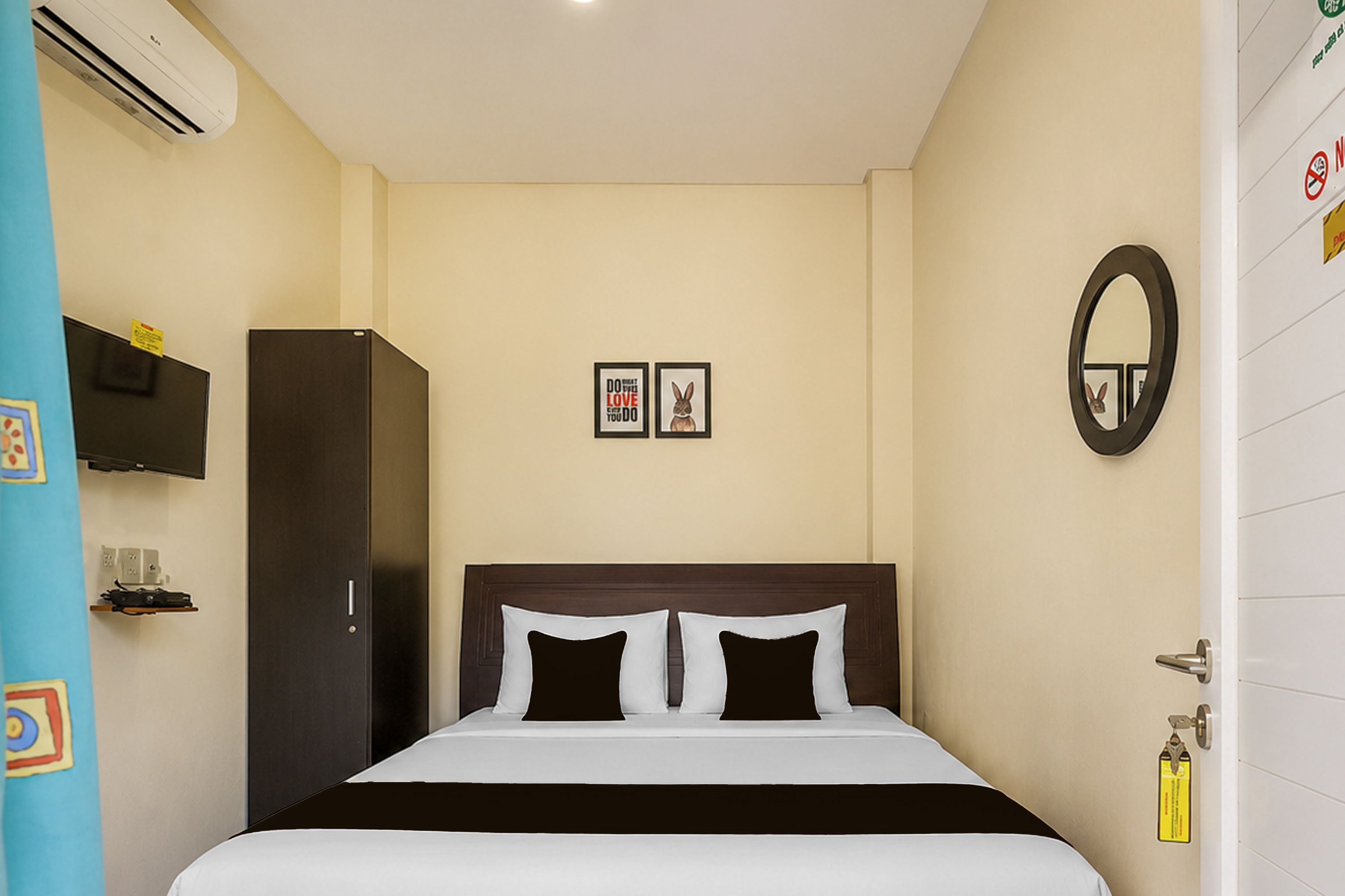 Una habitación de hotel con cama, armario, televisor y espejo.