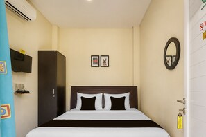 Una habitación de hotel con cama, armario, televisor y espejo.