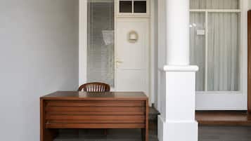 Una mesa de madera con una silla, una puerta blanca con un ventanal y un pilar blanco.