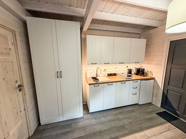 Eine kleine Küche mit weißen Schränken, einer Holz Arbeitsplatte und einer gefliesten Rückwand.