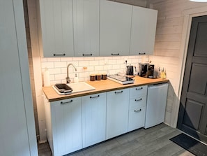 Eine Küche mit weißen Schränken, einer Holz Arbeitsplatte, einer Kaffeemaschine und einem Spülbecken.