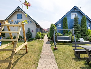 A pathway leading to two houses with 'Albos' signage, surrounded by greenery and outdoor seating. - Sommerhaus Albatros II by Interhome (Rewal)