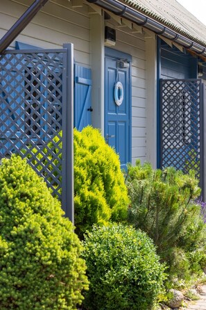 A house with a blue door, a blue gate, and a small garden with various shrubs. - Sommerhaus Albatros II by Interhome (Rewal)