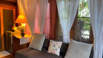 A cozy room with a sofa, a lamp, and a window with curtains.