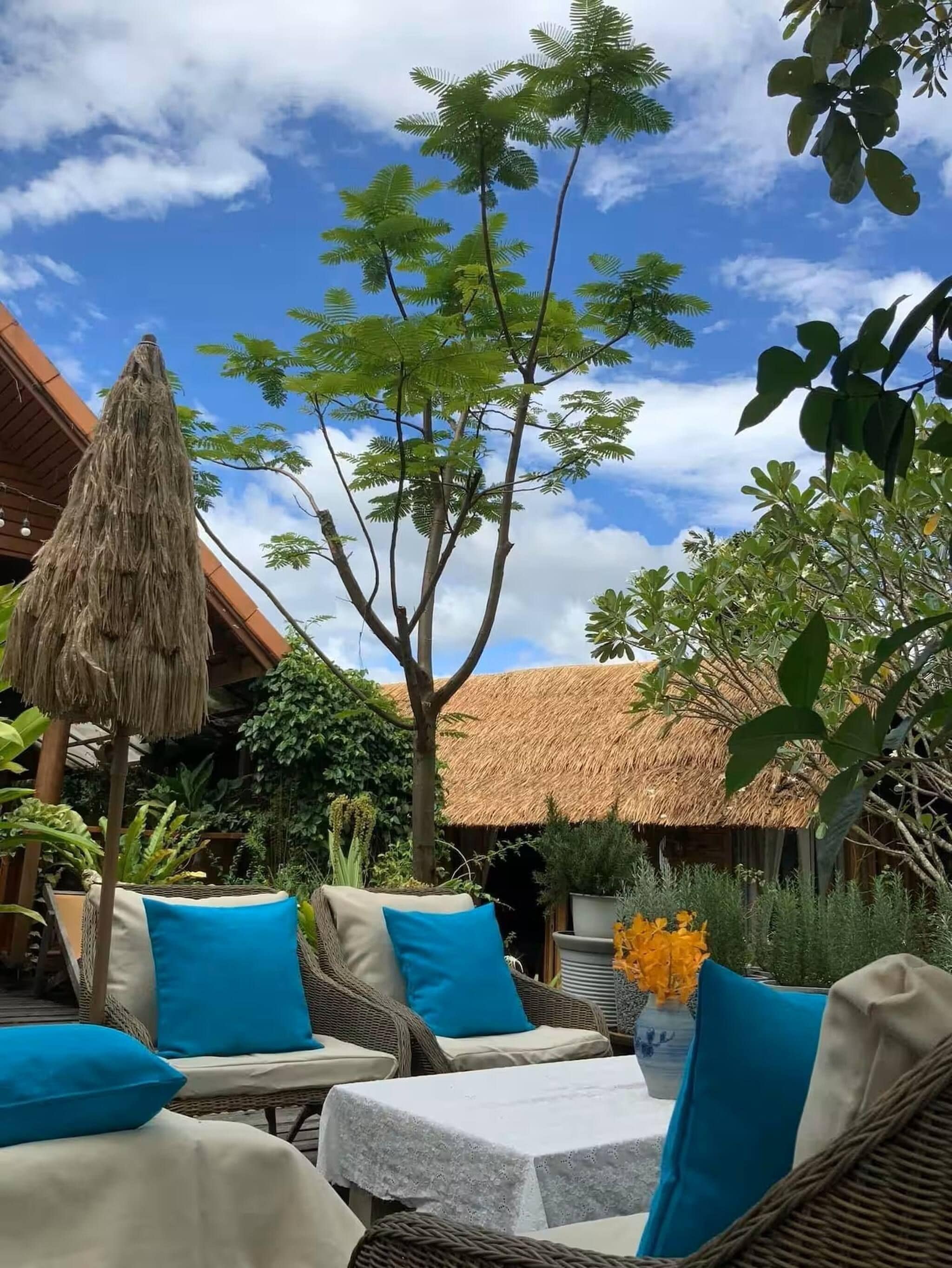 An outdoor seating area with wicker furniture and a thatched roof structure.