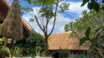 An outdoor seating area with wicker furniture and a thatched roof structure.
