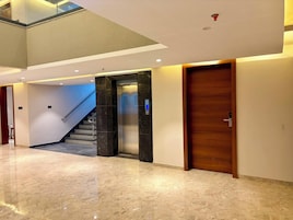 Un interior moderno con piso de mármol, puerta de madera y una escalera que lleva a un nivel superior.