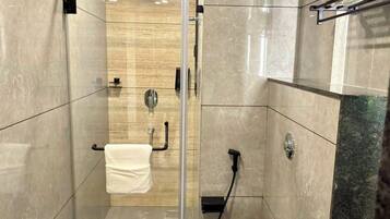 A modern bathroom with a glass-enclosed shower, a toilet, and a sink area.