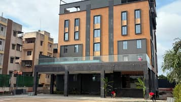 A modern multi-story building with a flat roof, large windows, and a covered entrance area.
