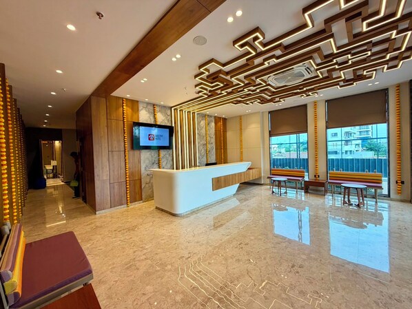 Un vestíbulo de hotel con mostrador de recepción, zona de estar y ventanas amplias.