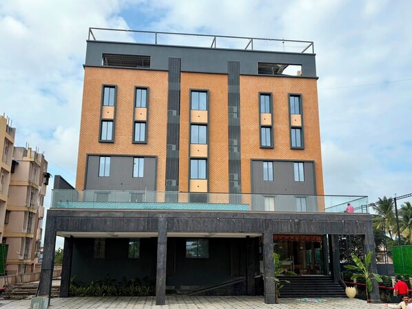 A multi-story building with a modern architectural design, featuring a flat roof, large windows, and a covered entrance area.