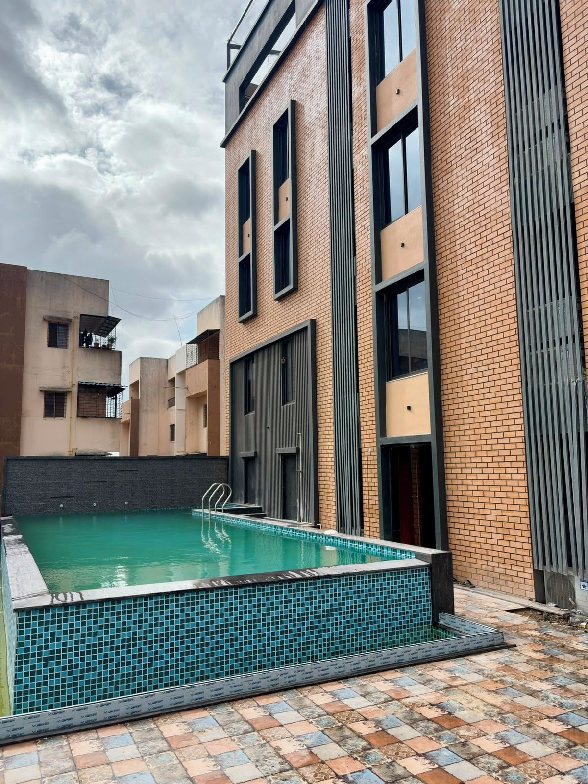 A residential building with a swimming pool, brick exterior, and large windows.