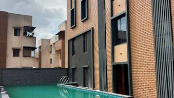 A residential building with a swimming pool, brick exterior, and large windows.