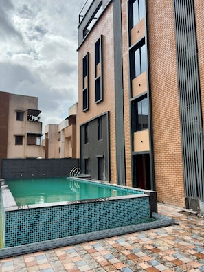 A residential building with a swimming pool, brick exterior, and large windows.
