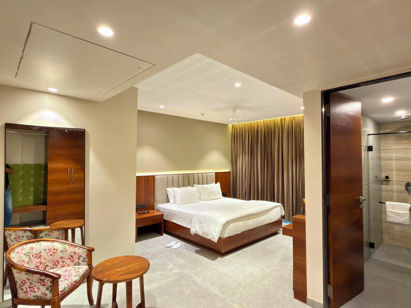 A hotel room with a bed, a chair, a desk, a wardrobe, and a bathroom.