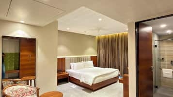A hotel room with a bed, a chair, a desk, a wardrobe, and a bathroom.