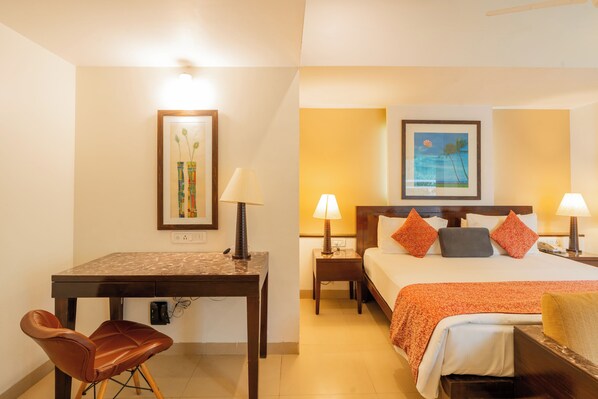 A hotel room with a bed, bedside tables, a desk, and a chair.