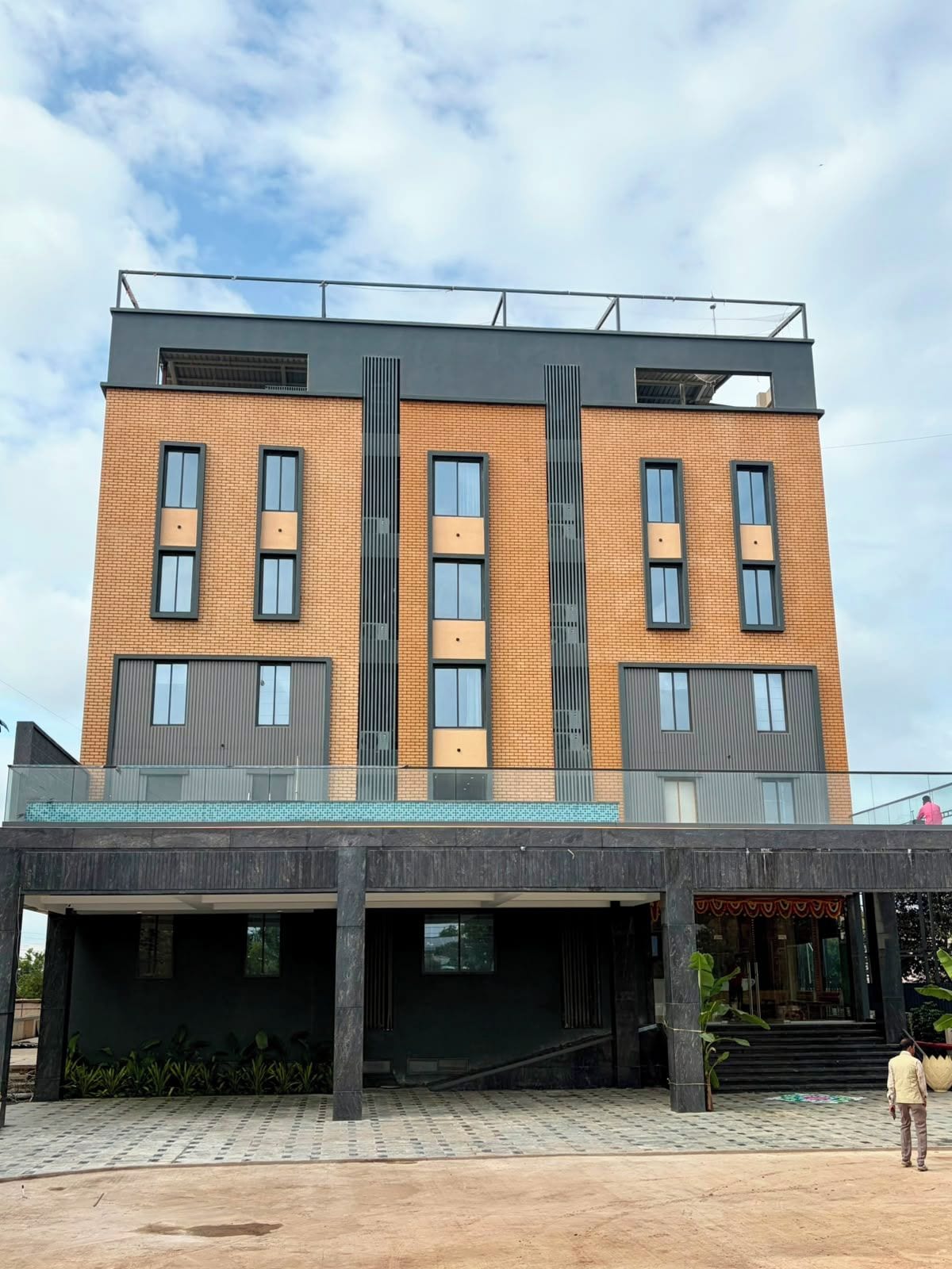A multi-story building with a flat roof, large windows, and a covered entrance area.