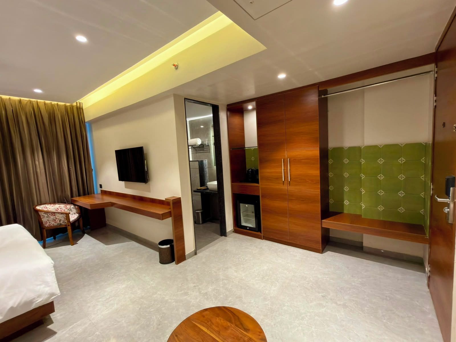 A hotel room with a bed, a desk, a TV, a wardrobe, and a bathroom.