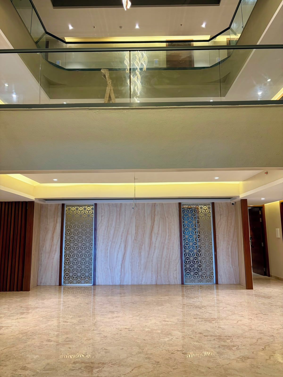A spacious lobby with a marble floor, a glass railing, and decorative panels.