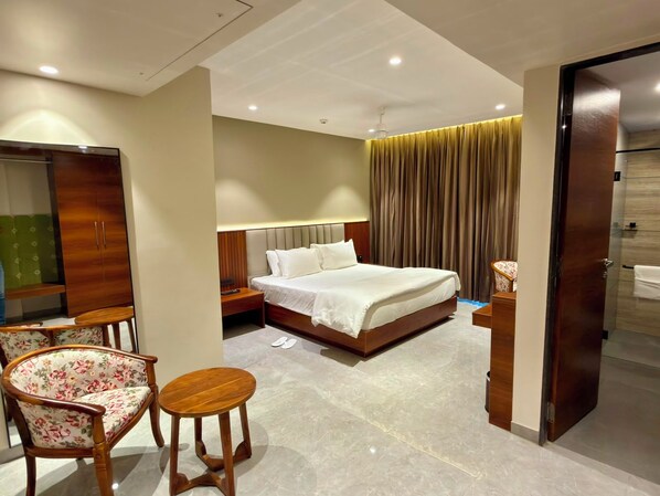 A hotel room with a bed, a desk, a chair, a wardrobe, and a bathroom.