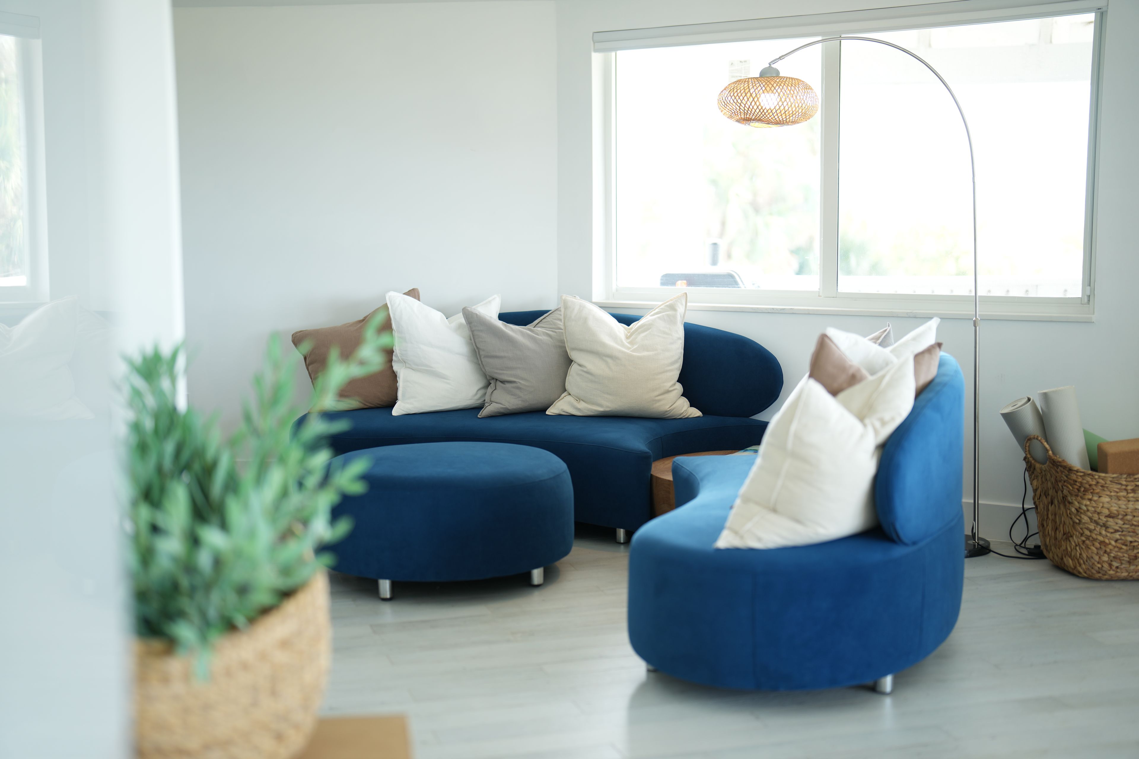 A modern living room with a sectional sofa, a round ottoman, and a floor lamp.
