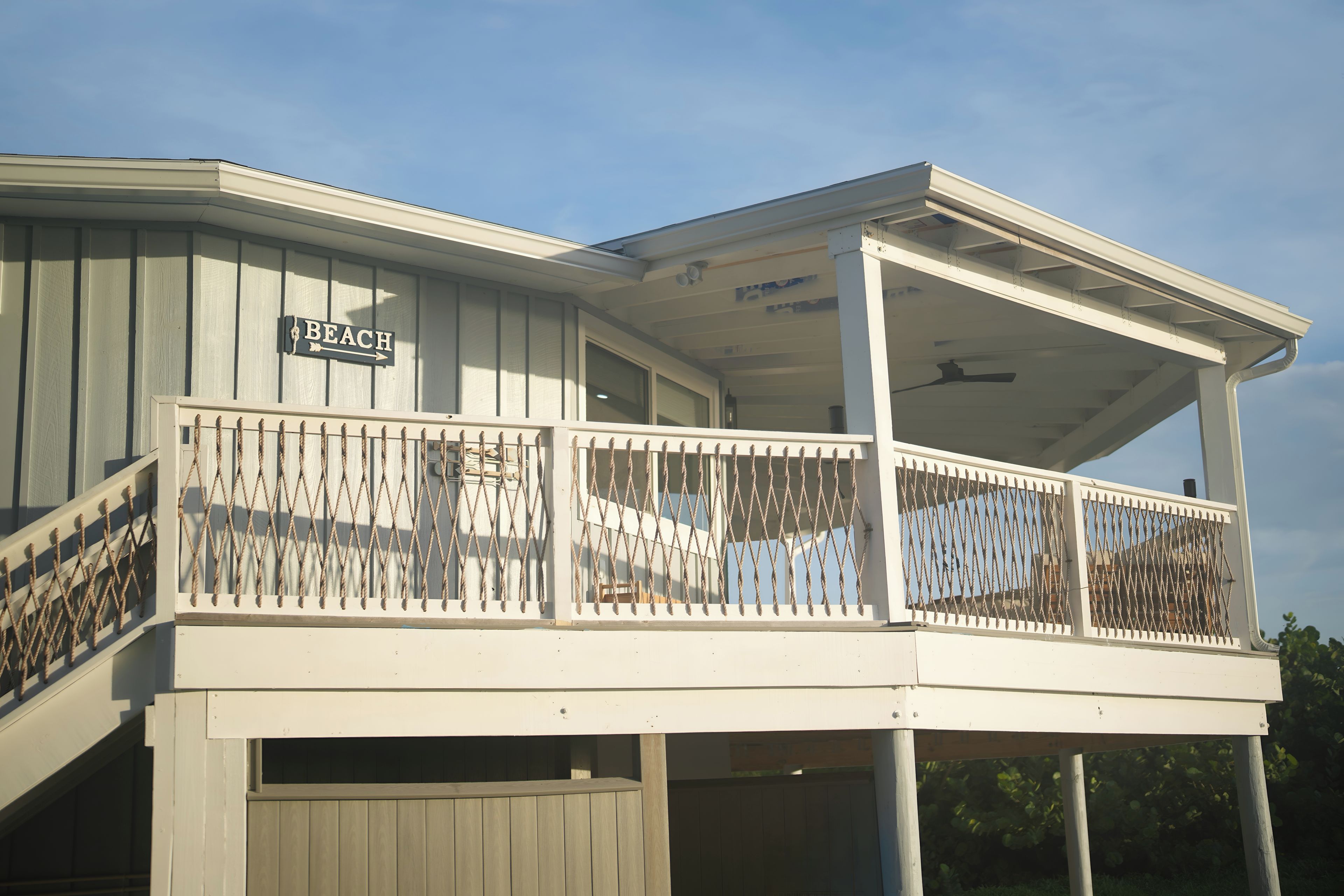Un bâtiment à deux étages doté d’un balcon, d’une enseigne indiquant « PLAGE » et d’un espace couvert avec un ventilateur de plafond.