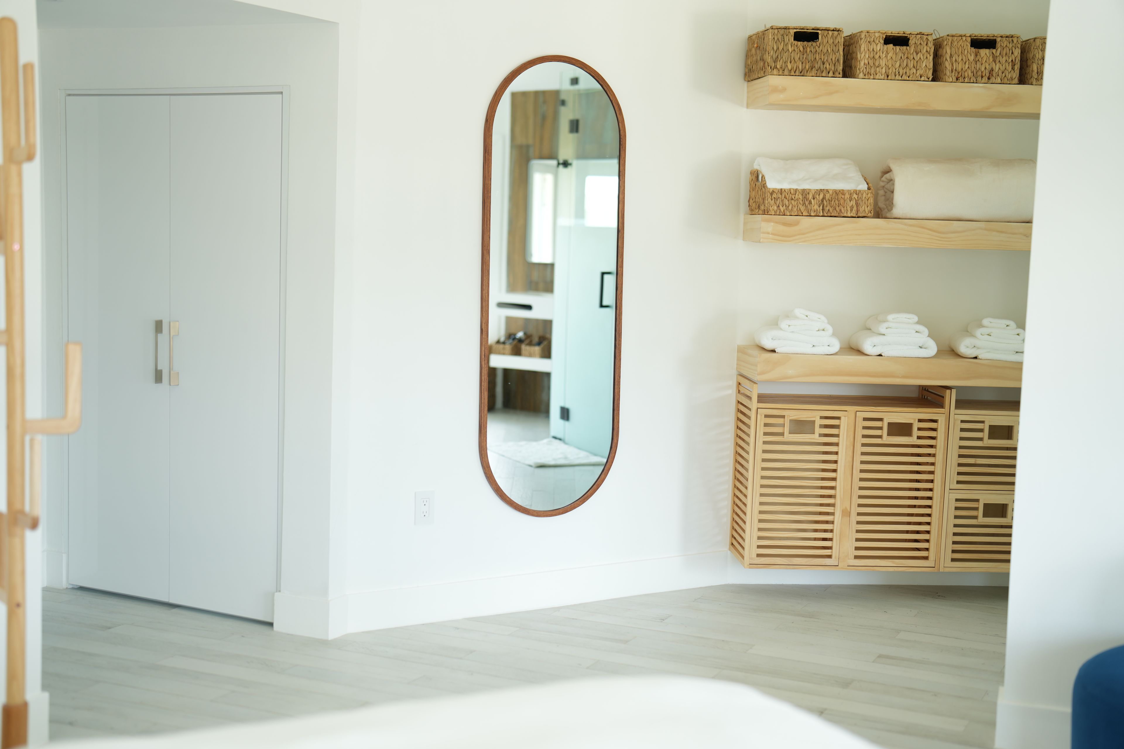 Une chambre d’hôtel avec une armoire en bois, un miroir et une porte blanche.