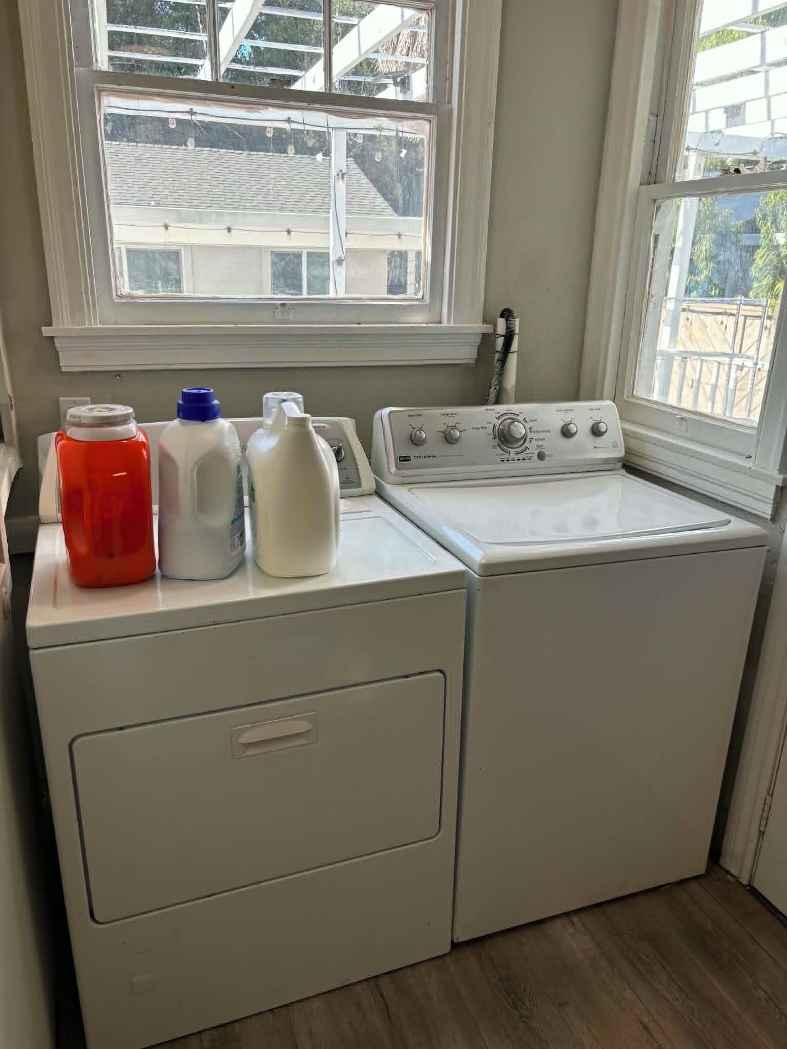 A front-loading washer and dryer in a laundry room with a window above.