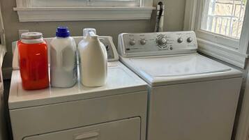 A front-loading washer and dryer in a laundry room with a window above.