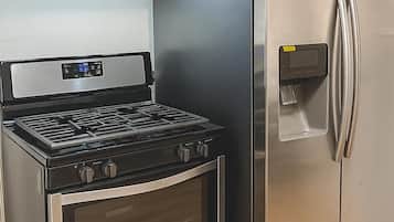 Una cocina con estufa, horno y refrigerador de acero inoxidable.