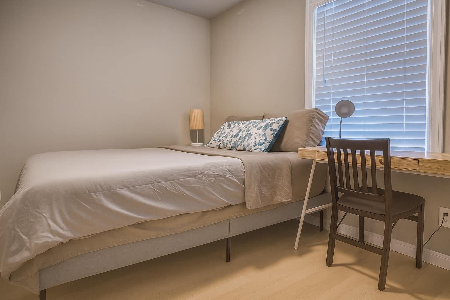 A bedroom with a single bed, a desk, and a chair.