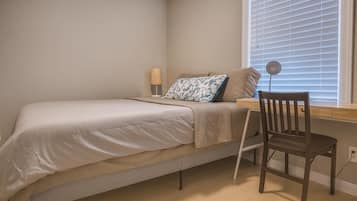 A bedroom with a single bed, a desk, and a chair.