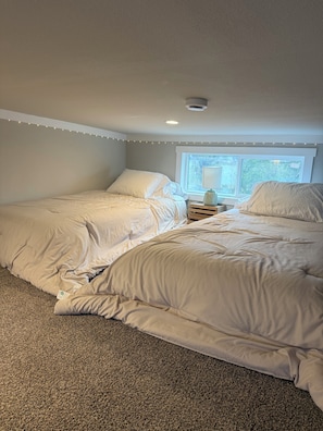 Une chambre avec deux lits, une fenêtre et une table de chevet.